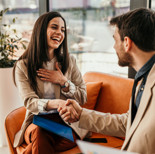 To forretningsfolk som smiler og håndhilser under et vellykket møte